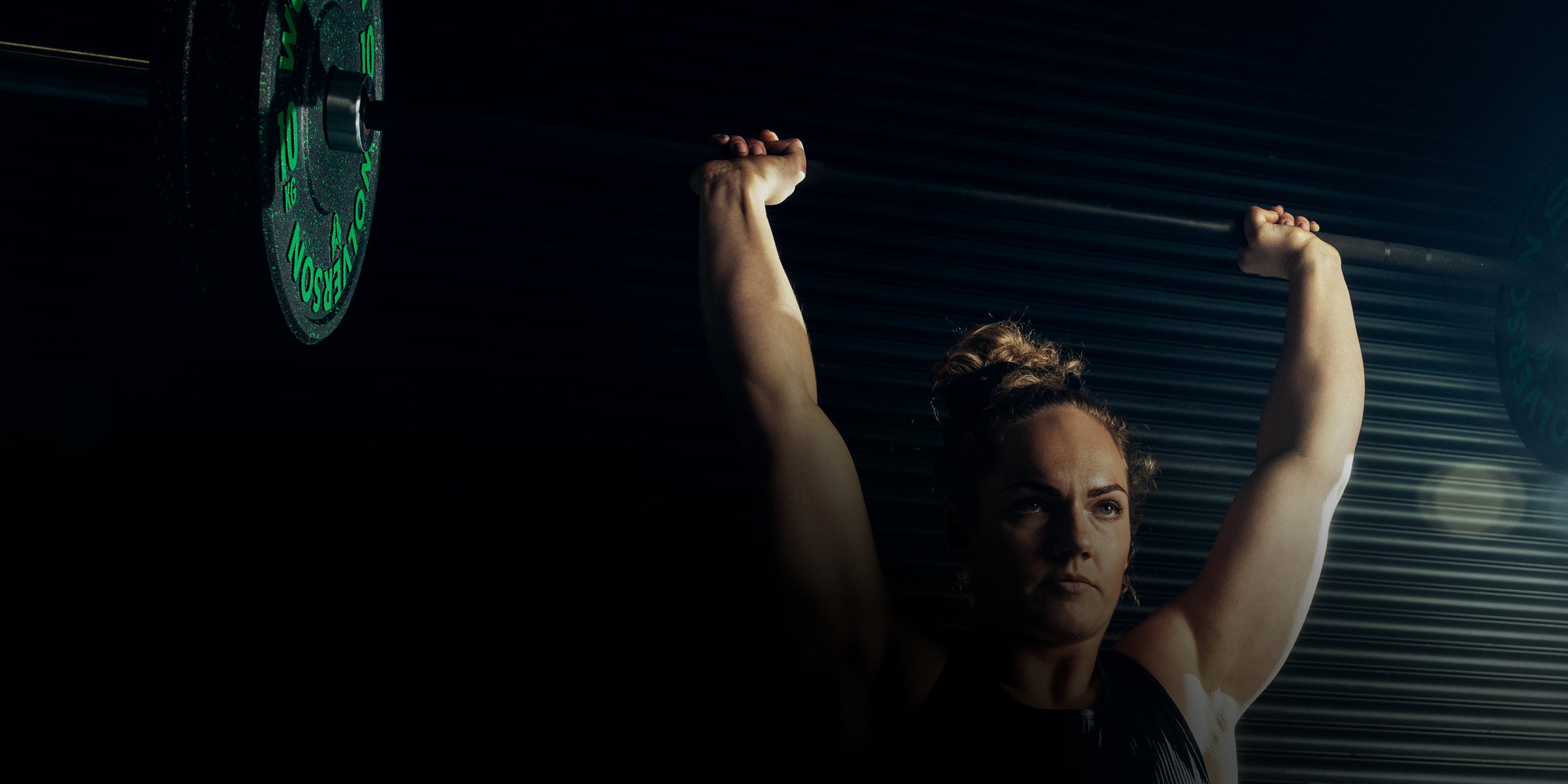 Athlete pressing a barbell overhead wearing TZ7 Ultra earbuds